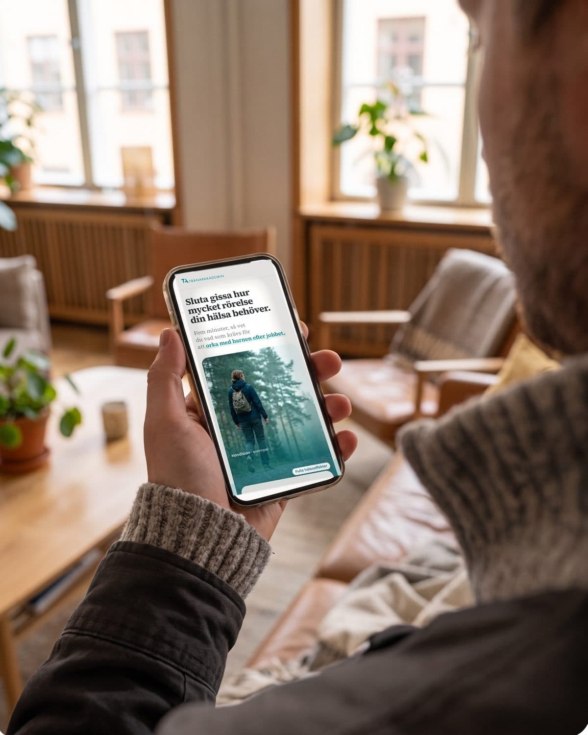 An employee doing Hälsokompassen on a phone at home on the sofa