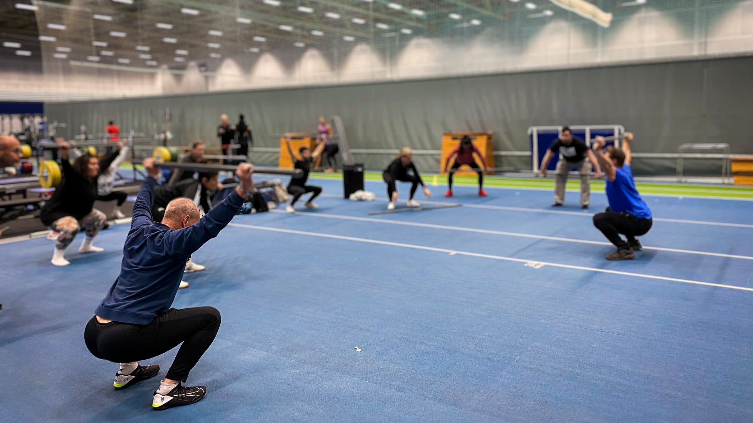 Klassen gör knäböj i hallen på Bosön med läraren längst fram