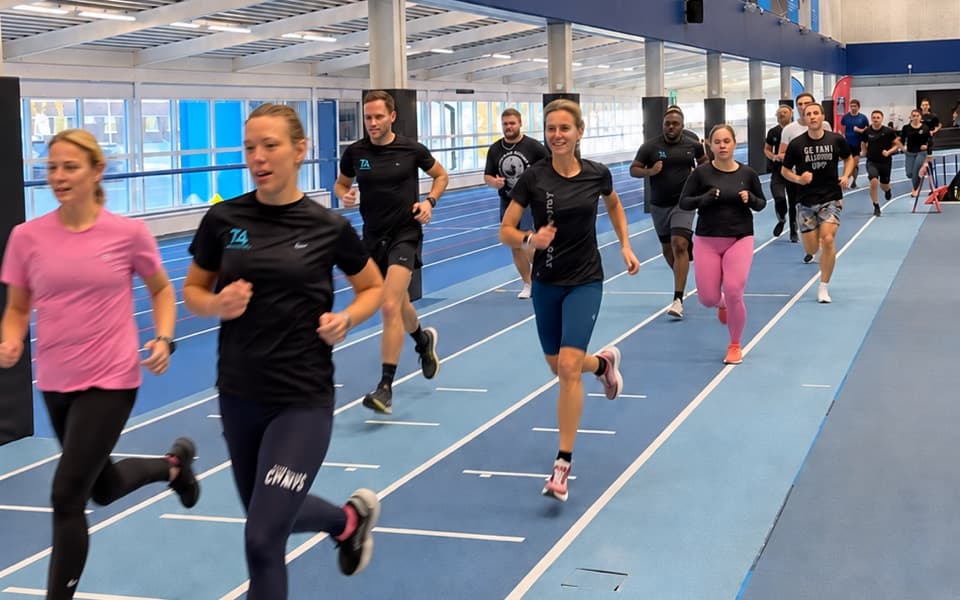 En grupp löpcoachstudenter springer tillsammans på inomhusbanan på Bosön