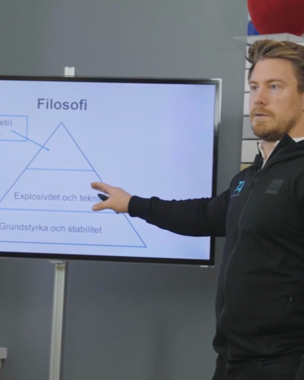 Stefan Ågren pekar på en skärm med en pyramid: grundstyrka och stabilitet i botten, explosivitet och teknik ovanför, under rubriken Filosofi